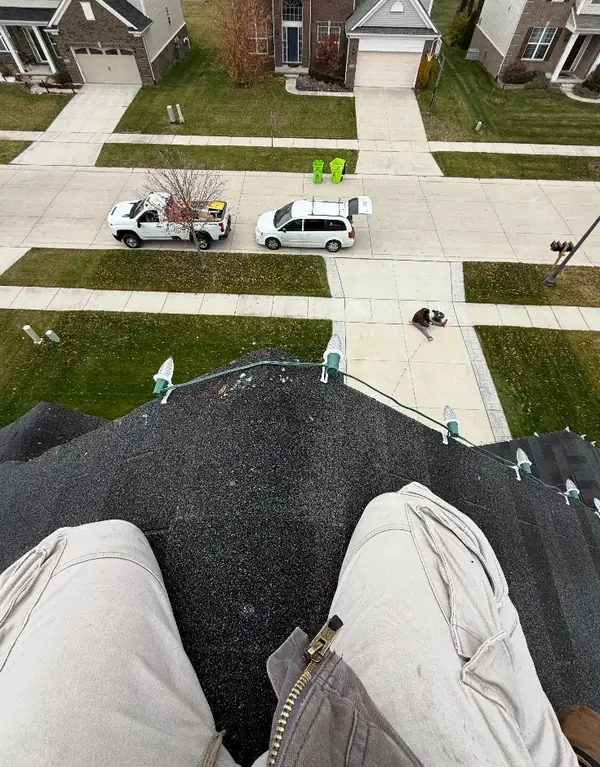 View from a roof edge looking down at the street, with light clips lined up along the shingles.